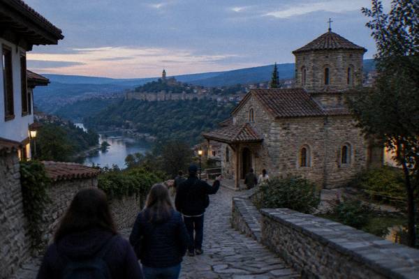 Small group with a guide on a cobbled street in Veliko Tarnovo, backs to camera