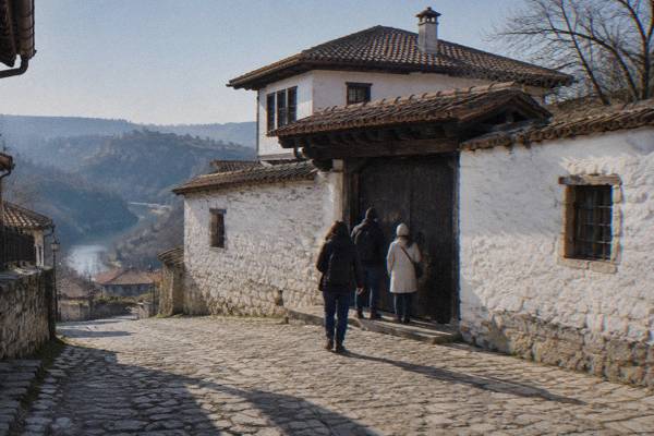 Visitors at a heavy wooden door in a high whitewashed wall of an old merchant house, early in the day, Konstantsalieva House