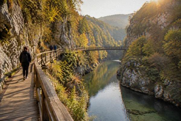 Walkers on a wooden walkway above a clear green canyon river, Emen Canyon