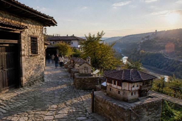 A park path lined with small scale models of historic buildings and visitors strolling, Arbanasi