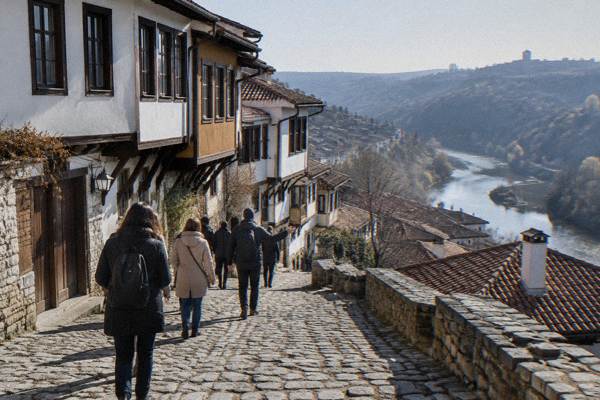 A guide leading a small walking group along a steep cobbled street of painted houses, Gurko Street