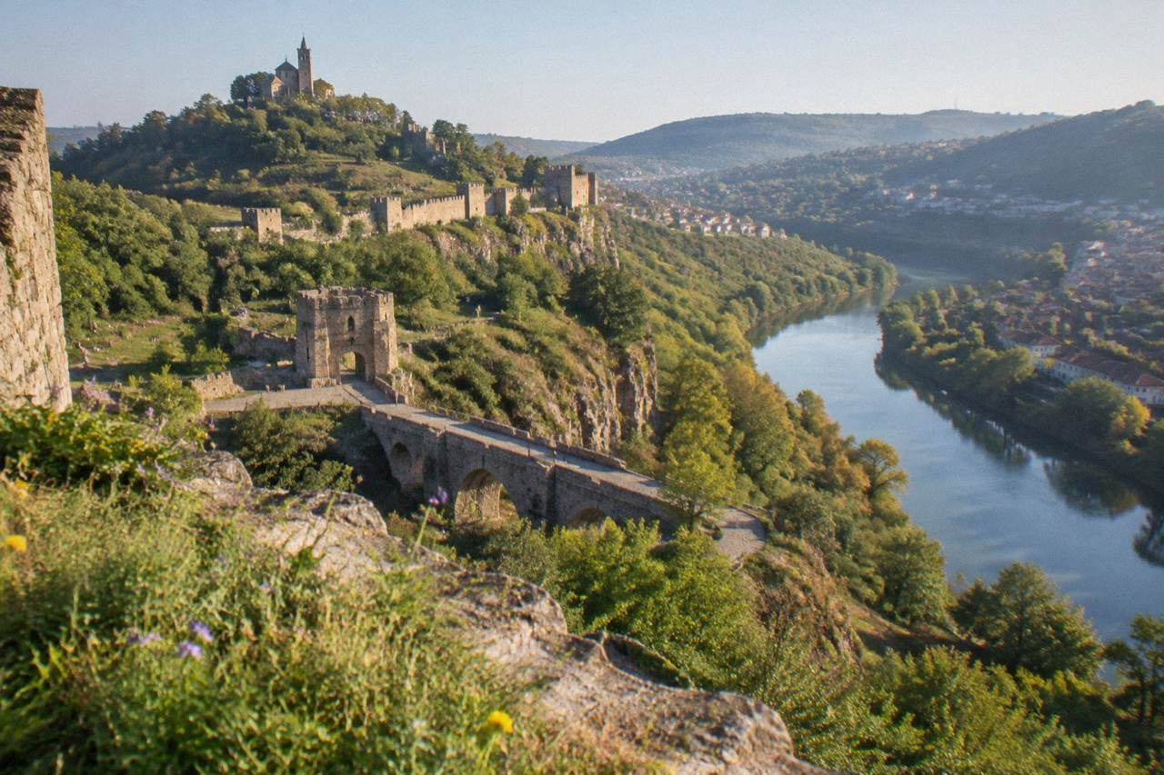 Hillside houses and a stone fortress wall above a river bend in a Bulgarian town