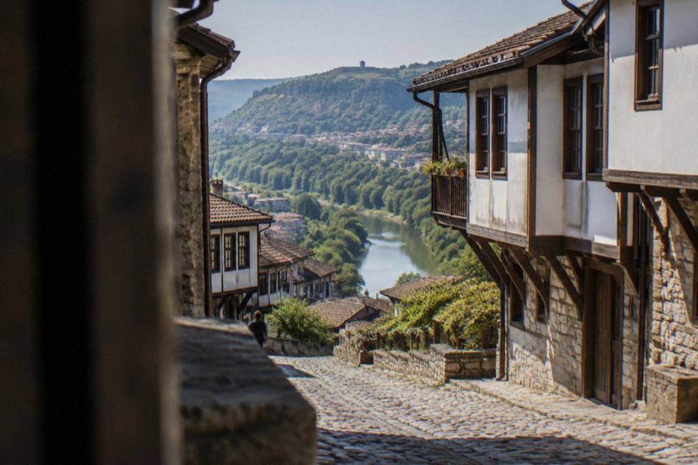 A cobbled street of old houses above a river bend in an old town
