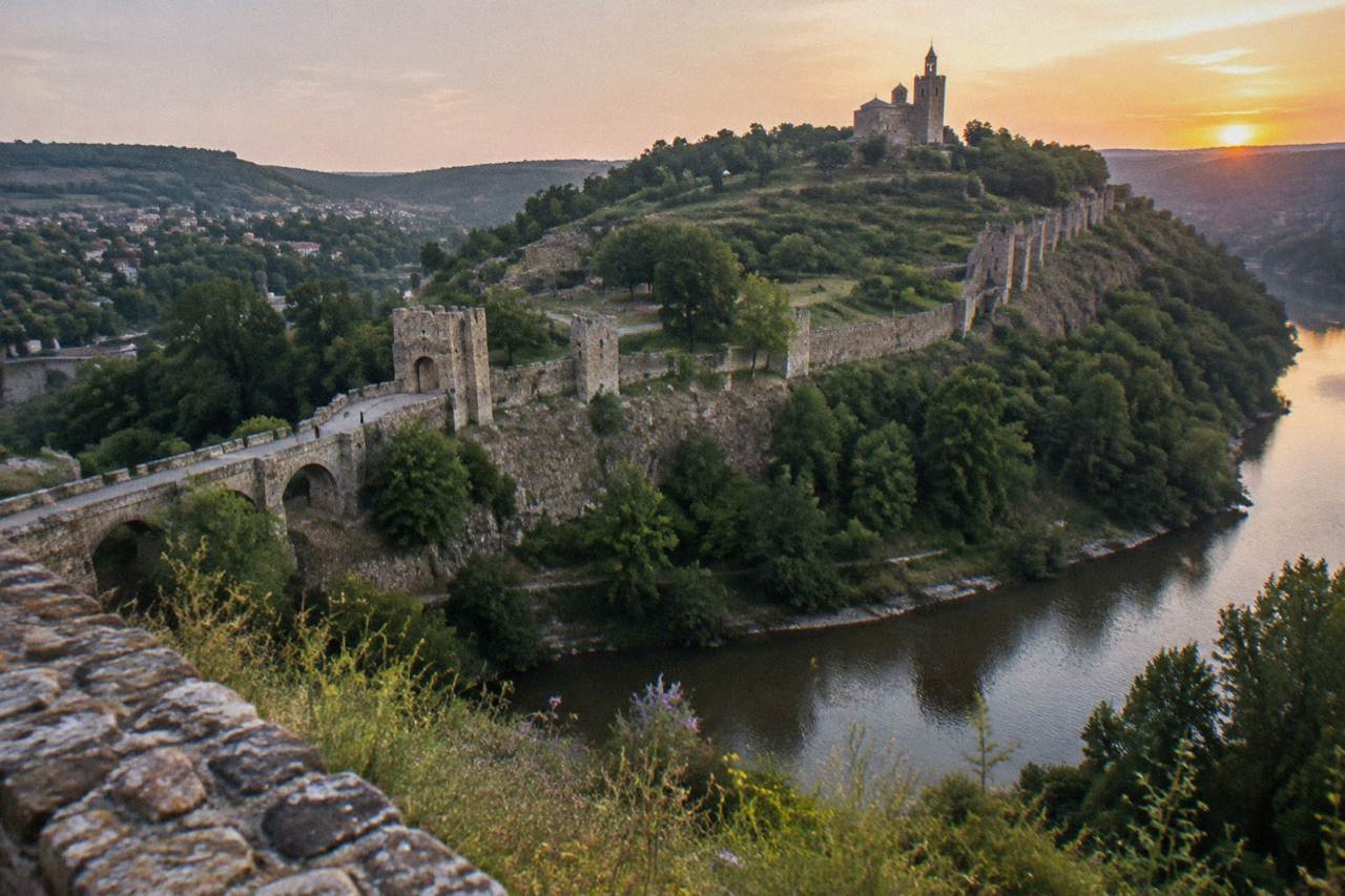 Tsarevets Fortress hill rising above the Yantra river at dusk in Veliko Tarnovo