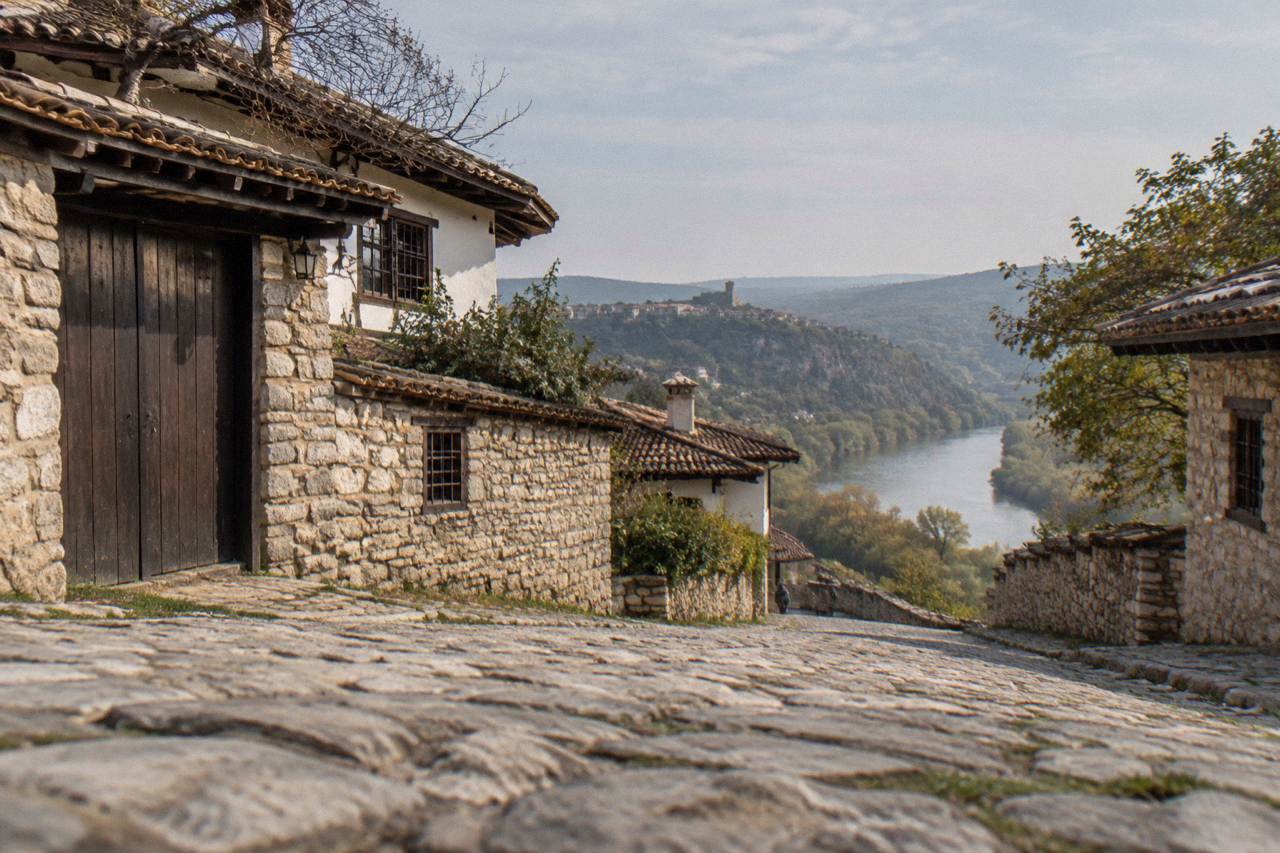 Stone houses with tiled roofs on a green plateau overlooking a river valley
