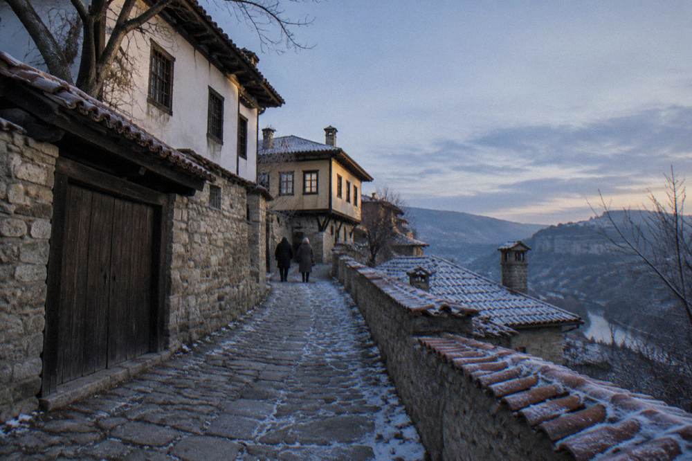 Frost-covered stone rooftops of a village on a plateau under a pale winter sky