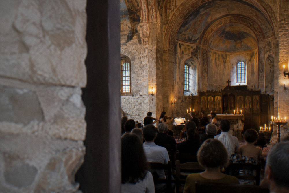 A stone church interior with an evening concert crowd and candlelight