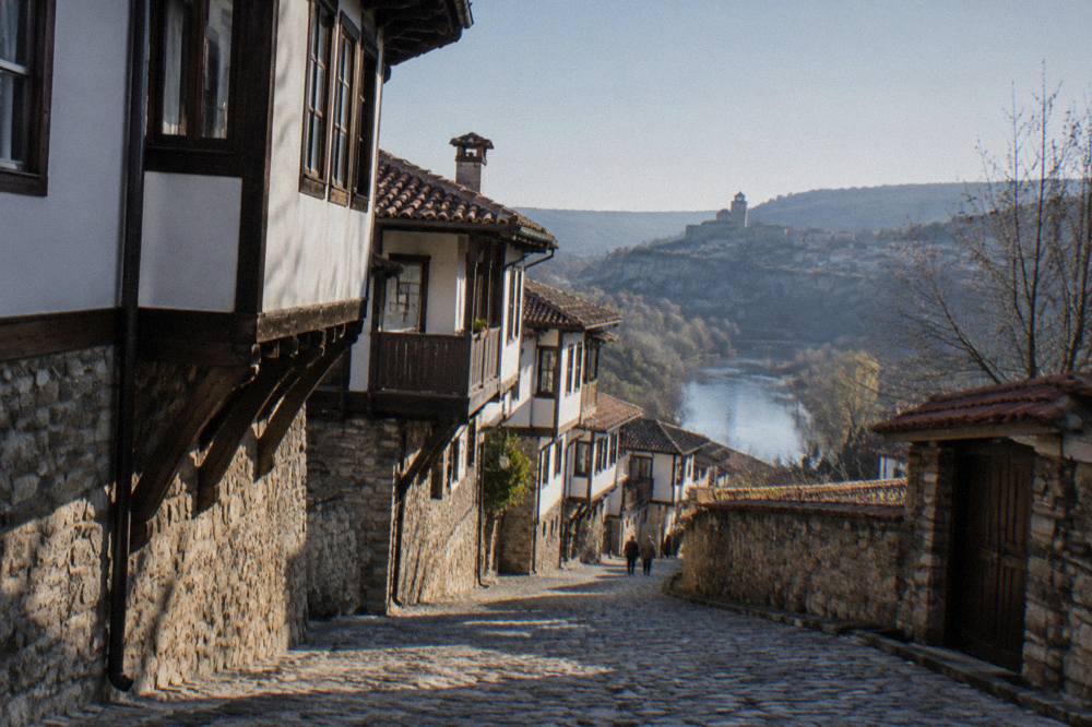 Steep cobbled street with warm lamp light on old house fronts, no people