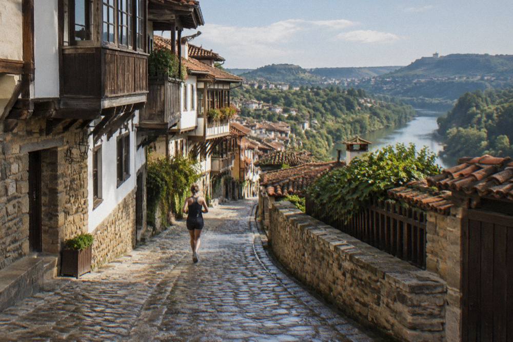 Old-town stone lane with houses stepping toward a fortress hill