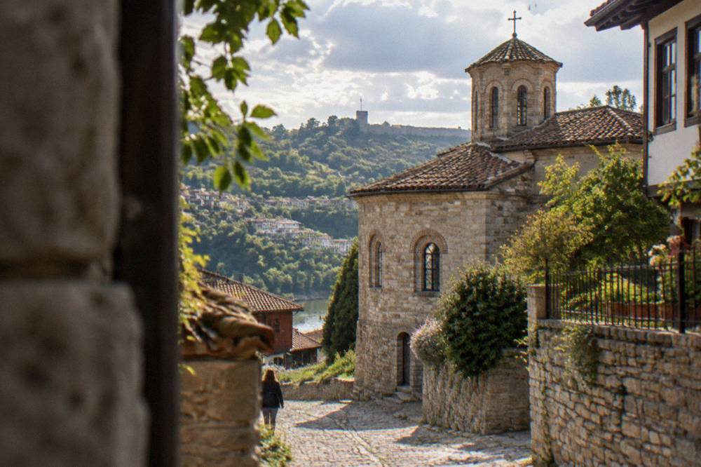 A stone church with arched windows beside a cobbled lane in an old Bulgarian quarter