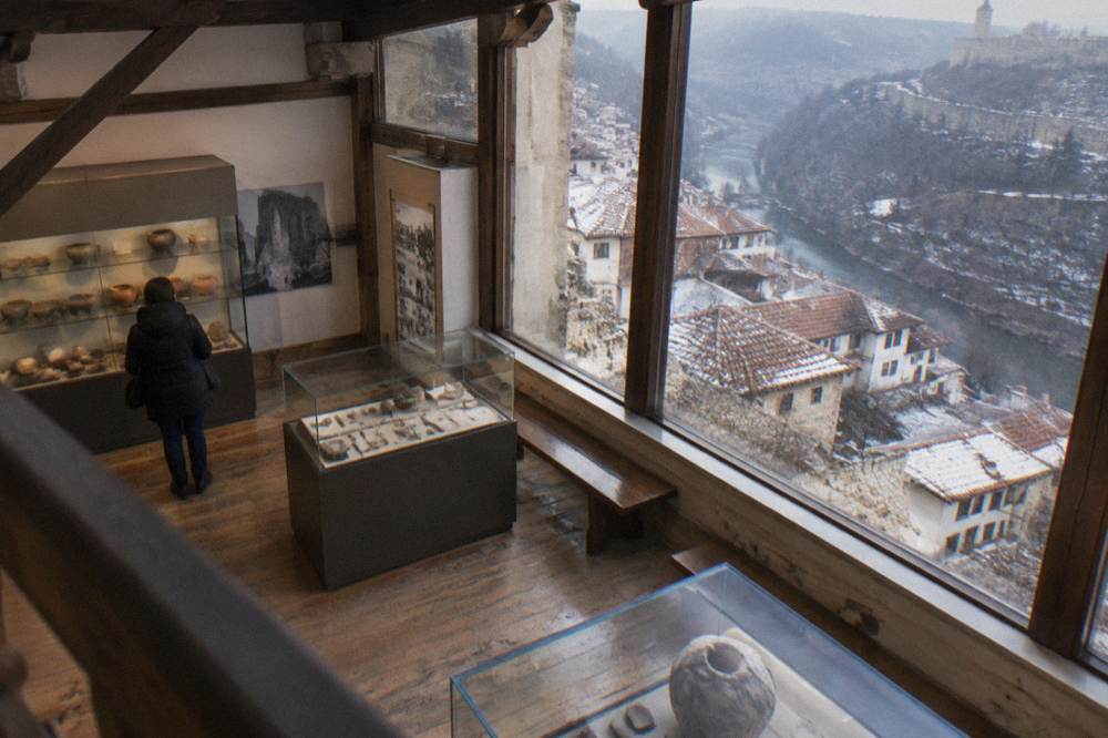 A museum interior with wooden beams and displays behind glass panels