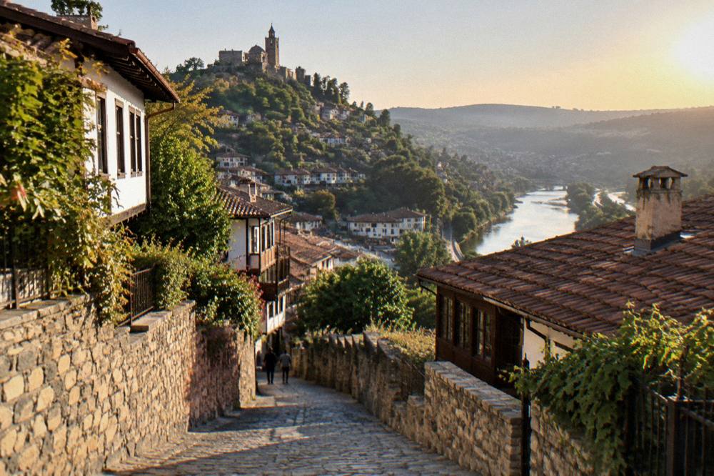 Evening light over rooftops and a river bend seen from an old town street