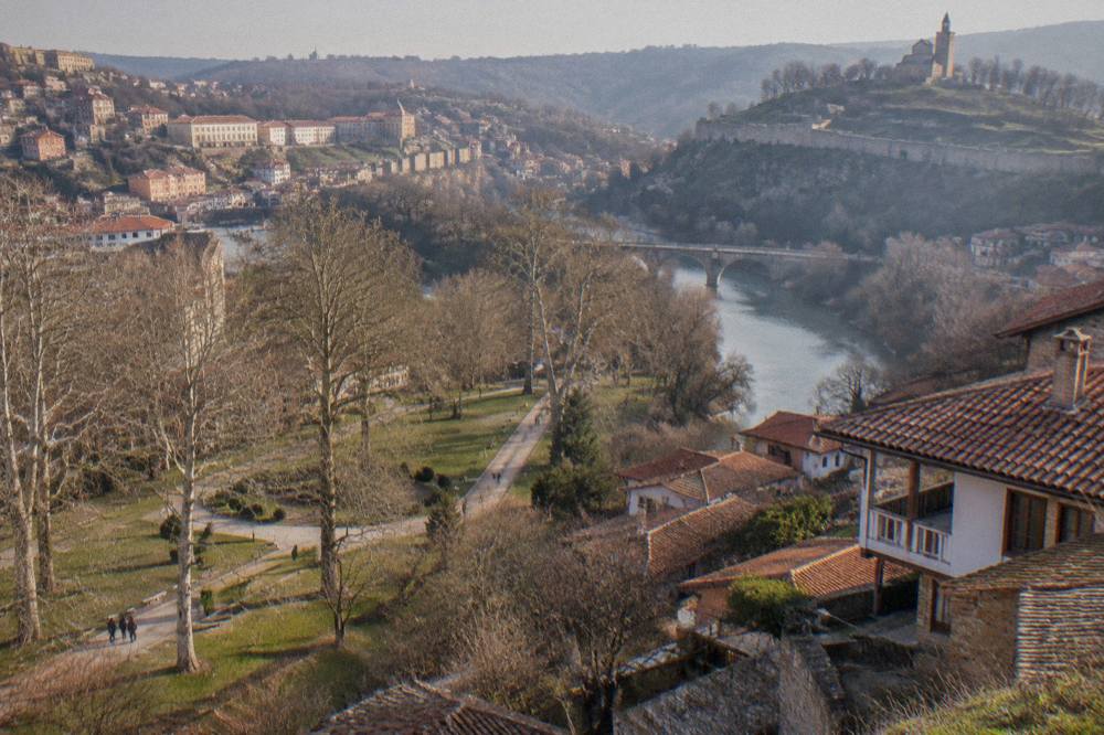 A stone monastery building among green hills in the Bulgarian countryside