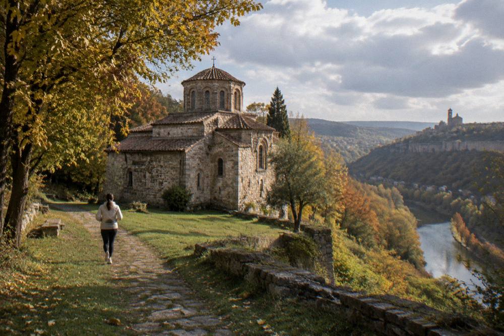 Autumn trees along a river gorge with a historic church tucked at the base of a hill