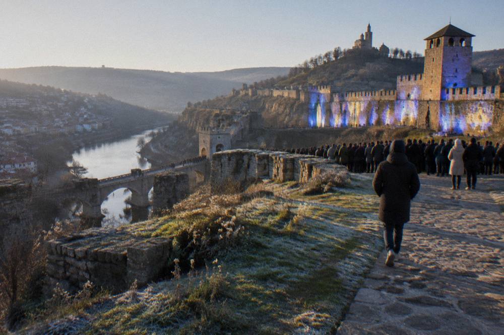 Crowd watching a light show projected onto fortress walls at night