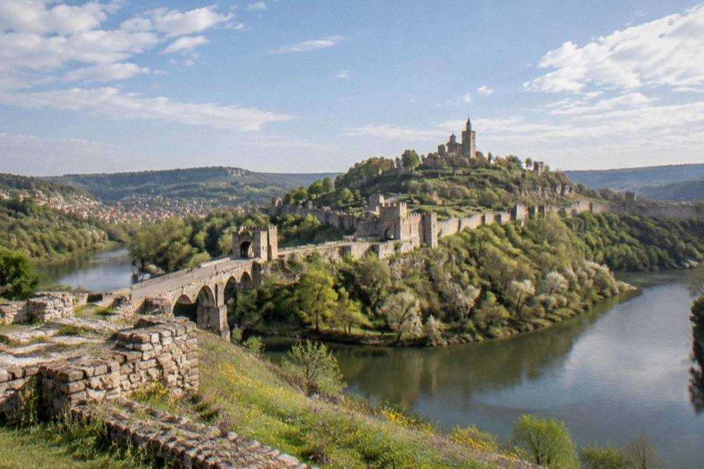 Stone fortress walls on a hill above a river bend in Veliko Tarnovo