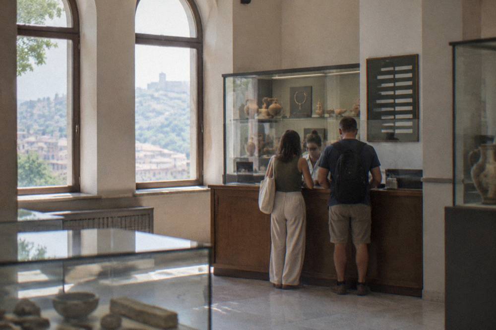 A ticket counter in a Bulgarian museum with a price board and a glass display case behind it