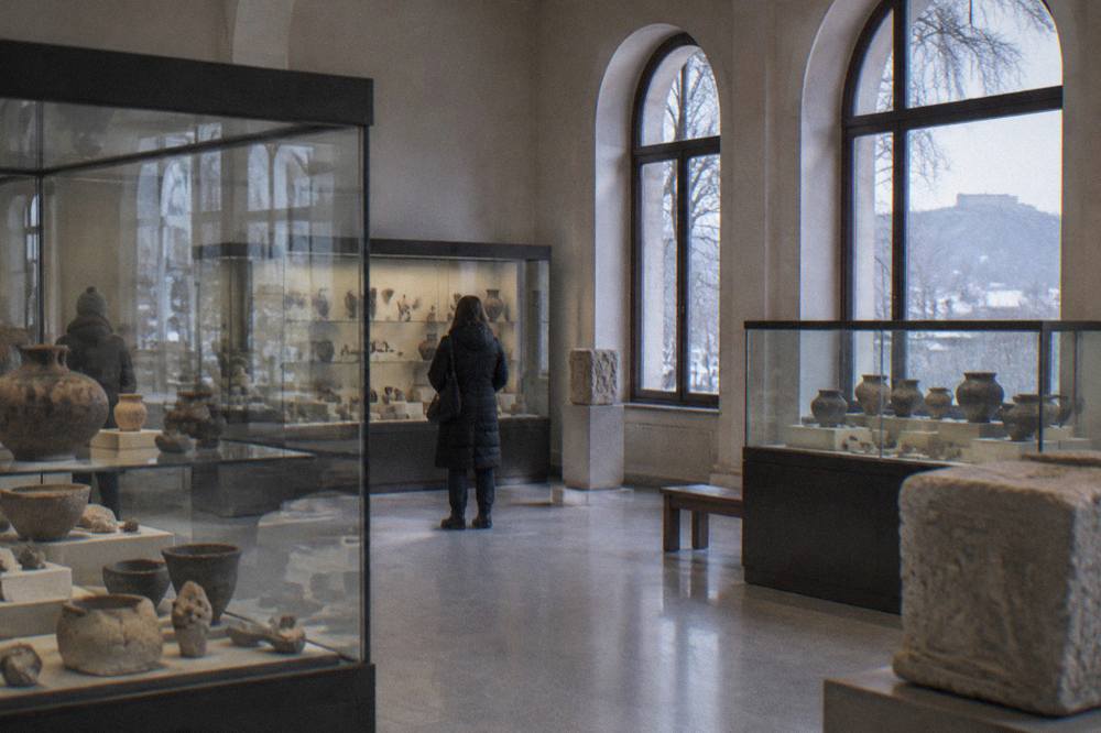 A quiet archaeological museum hall with glass cases of pottery and stone fragments