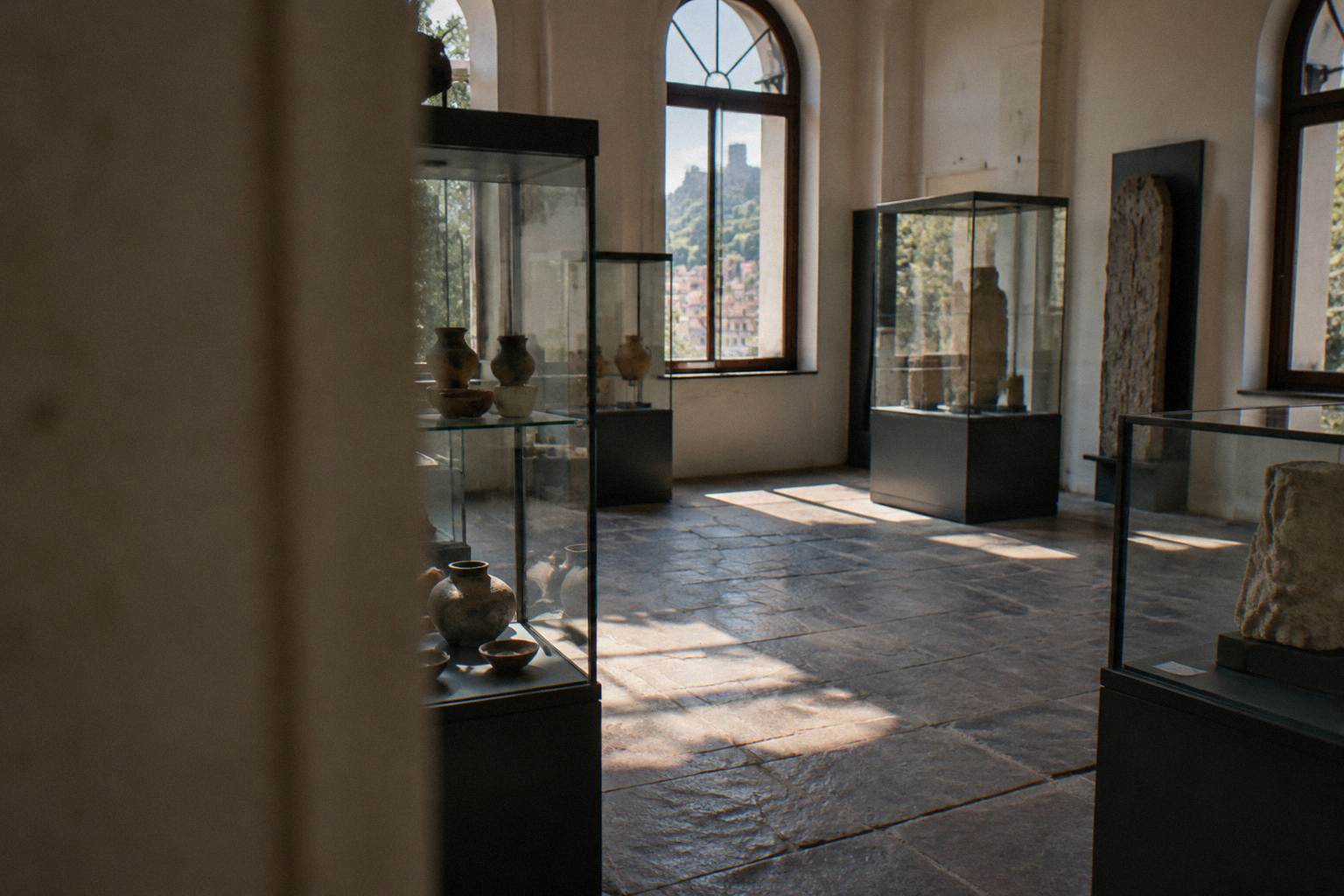 Museum gallery with display cases and stone floor, empty