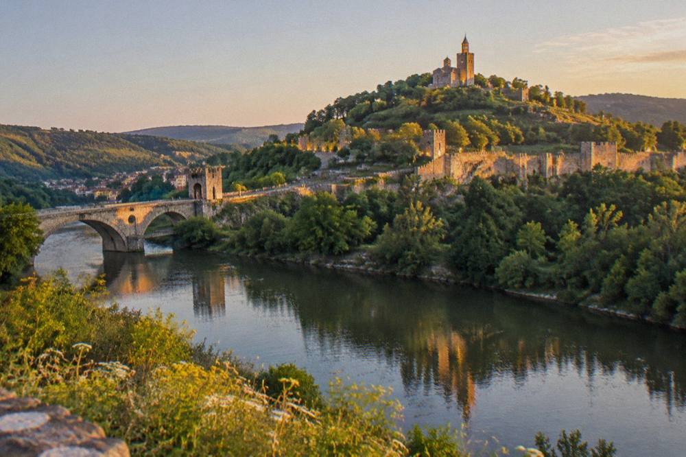 An evening view of illuminated Tsarevets Hill from across the Yantra river in Veliko Tarnovo