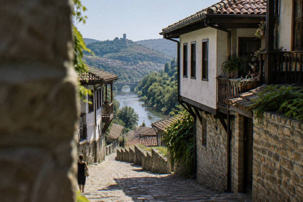 A narrow old town lane with stone walls leading down toward a river crossing
