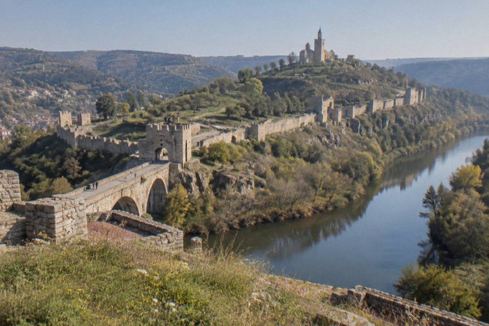 The stone fortress walls and hilltop cathedral of Tsarevets seen across the Yantra river