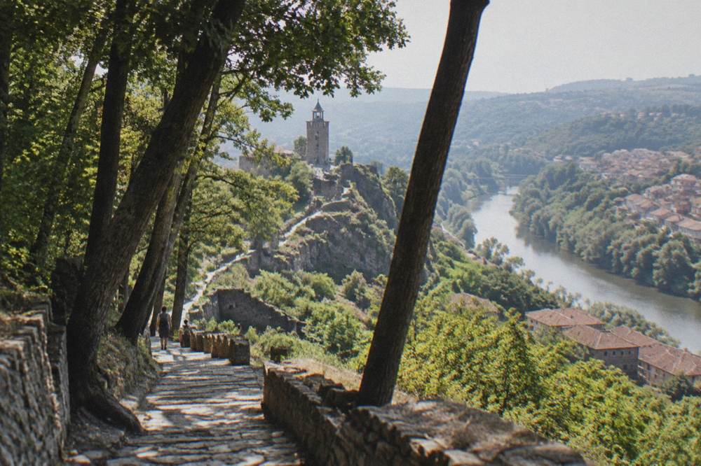 Stone ruins and a restored tower on a hilltop above a winding river