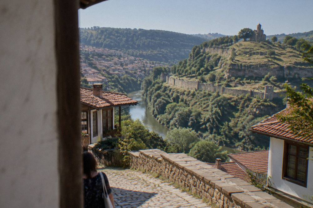 A cobbled street with old houses overlooking a valley in daylight