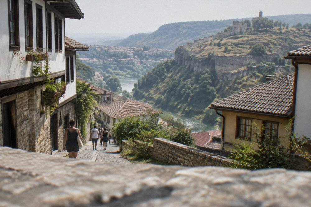People walking on a narrow cobbled street between old houses on a slope