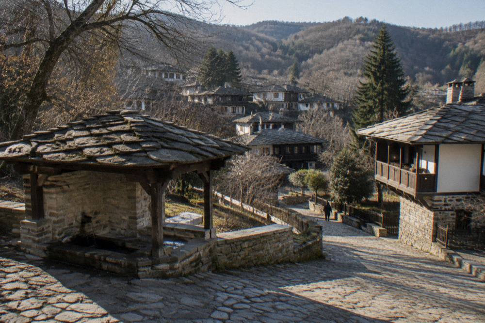 Old stone fountain with wooden roof at the edge of the village