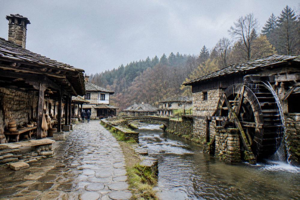 Wooden waterwheel and craft workshops along the stream at an open-air museum