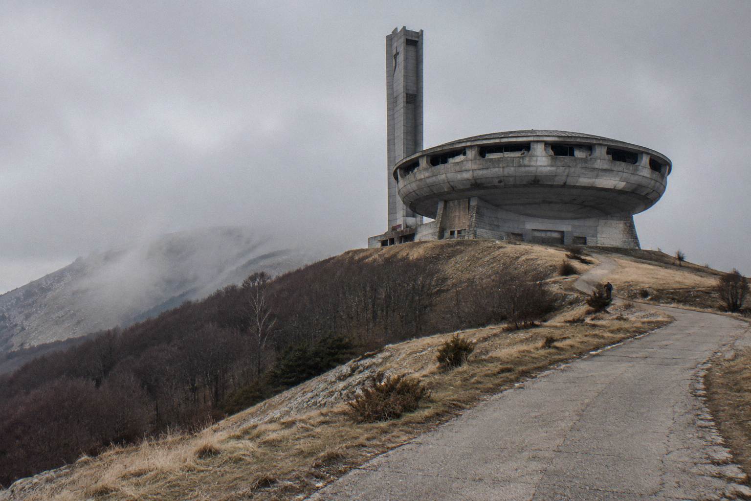 Large concrete saucer-shaped monument on a misty mountain ridge