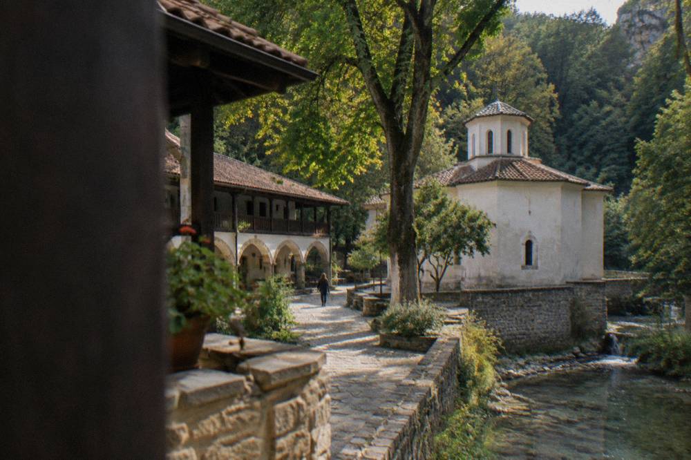 A stone monastery courtyard with arched walkways and trees