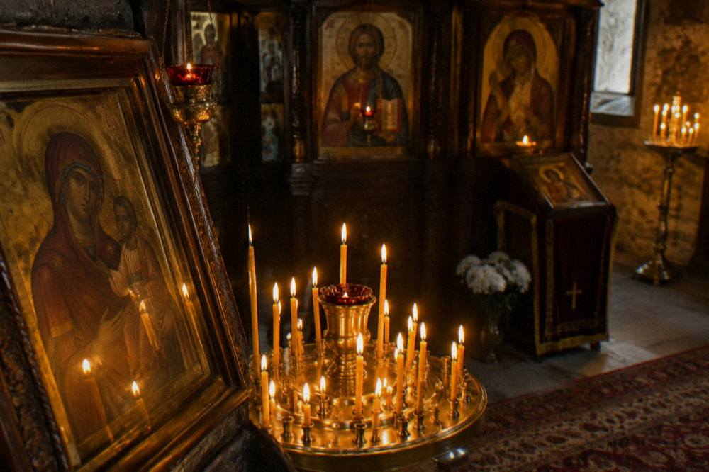 A candle-lit interior of an Orthodox church with icons