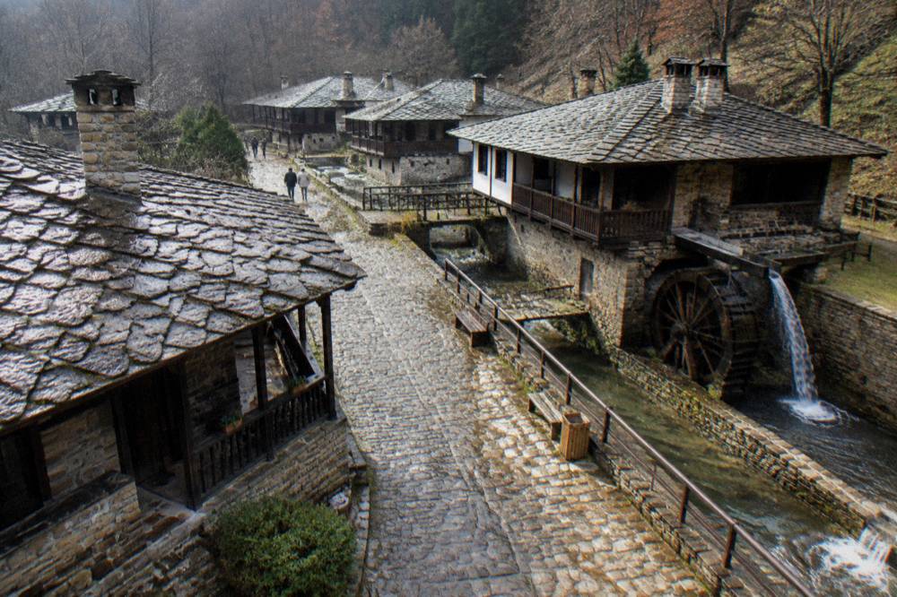 Old Bulgarian revival houses with stone bases and wooden verandas on a village lane
