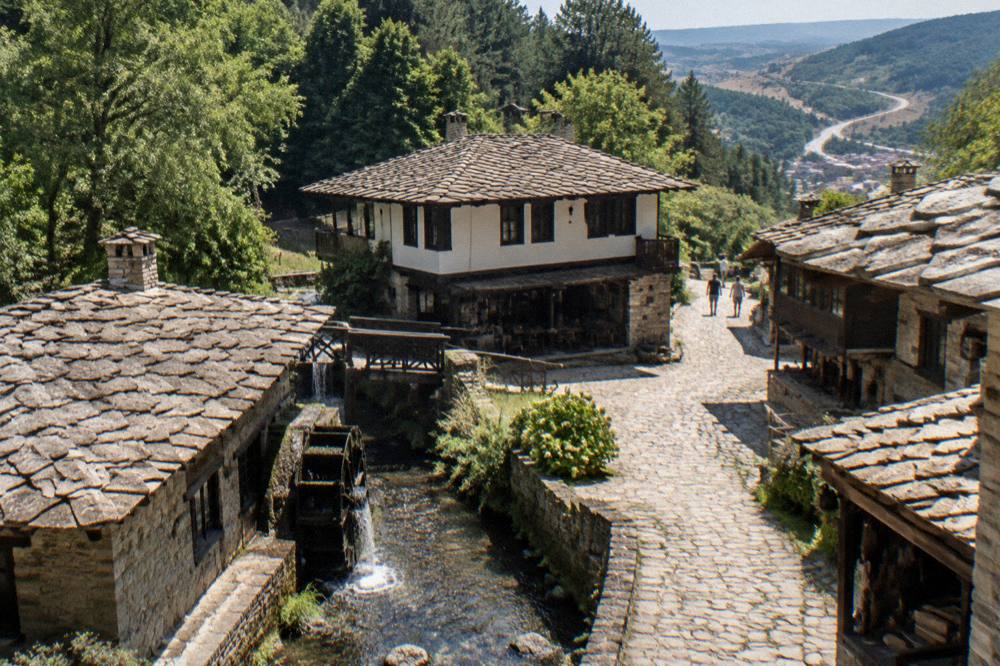 Winding road through green Balkan foothills toward a distant town