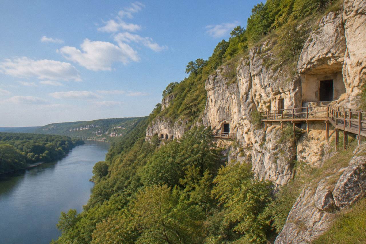 Rock cliffs above a river valley with carved church openings high in the stone face