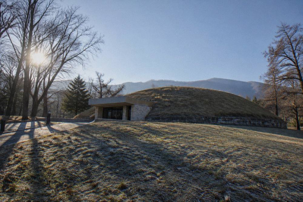 A grass-covered Thracian burial mound under a wide sky