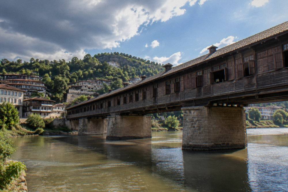 Old houses stacked on a wooded hillside above a river in a Bulgarian town