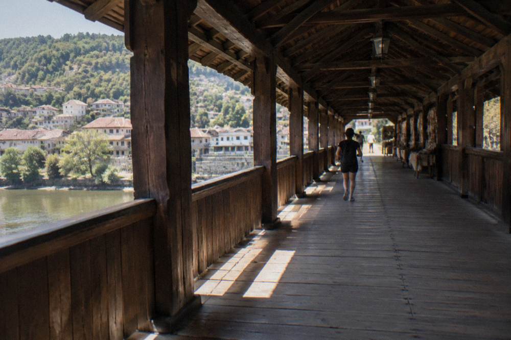 The interior of a covered wooden bridge with shops and light at the far end