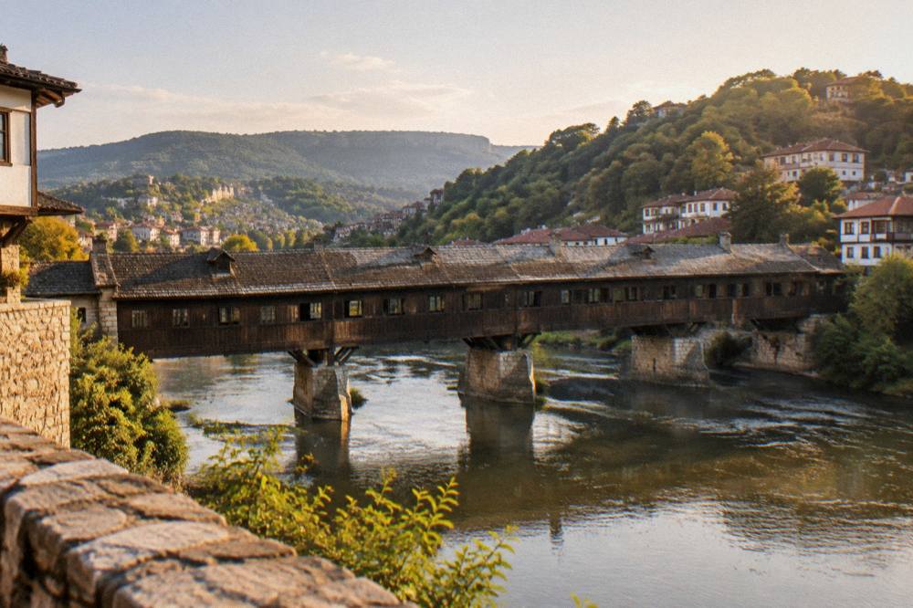 A panoramic view over a Bulgarian river town at golden hour with a bridge below