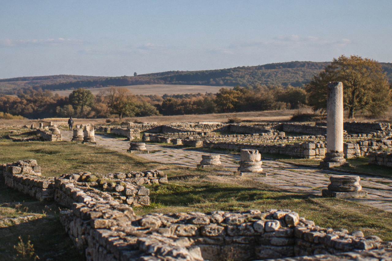 Stone foundations of a Roman ruins site in open countryside under a wide sky
