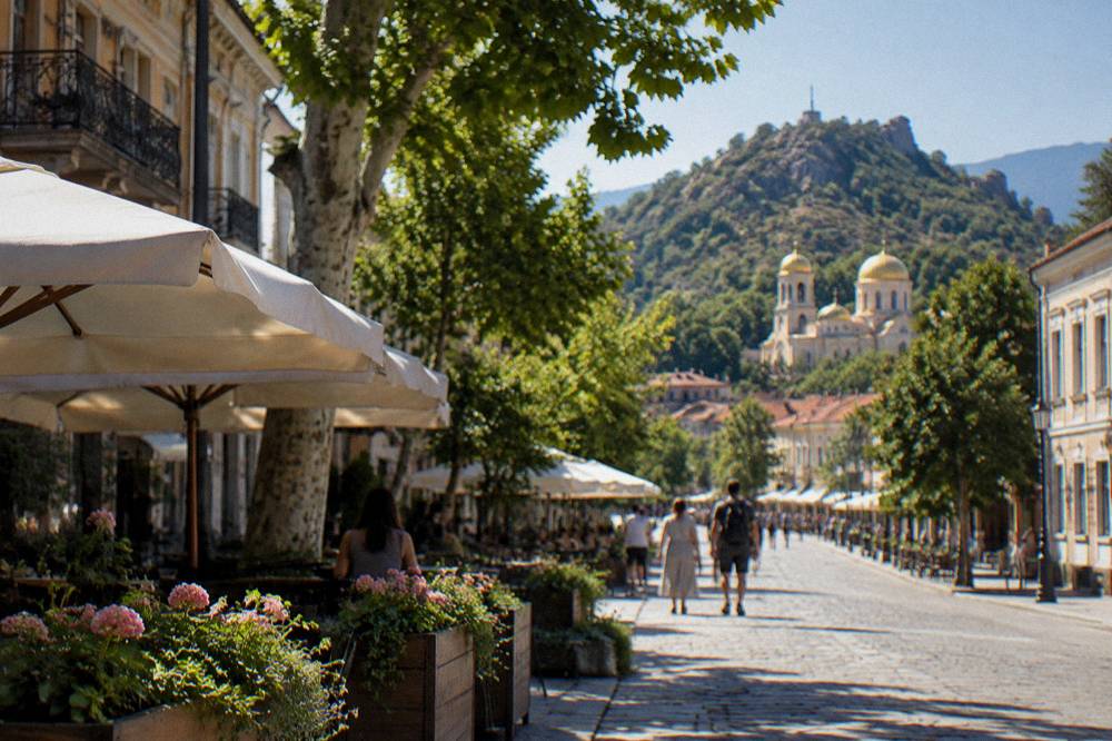 A church with golden domes standing above a village street with mountains behind