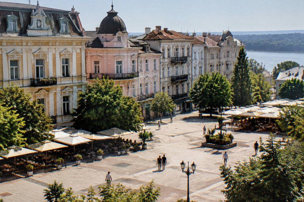 A wide city square with cafes and ornate building facades in daylight
