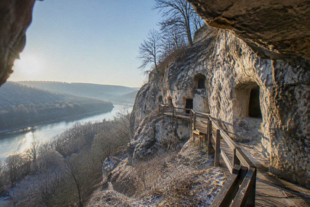 Medieval rock-hewn church chambers carved into a cliff above a river gorge