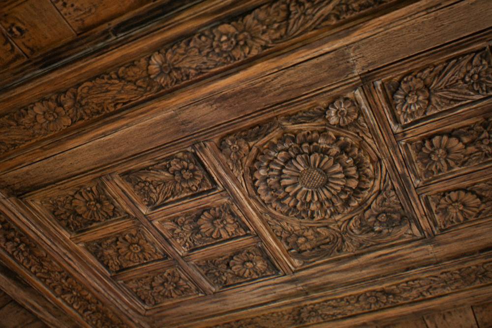 A carved wooden ceiling with floral patterns inside a museum house