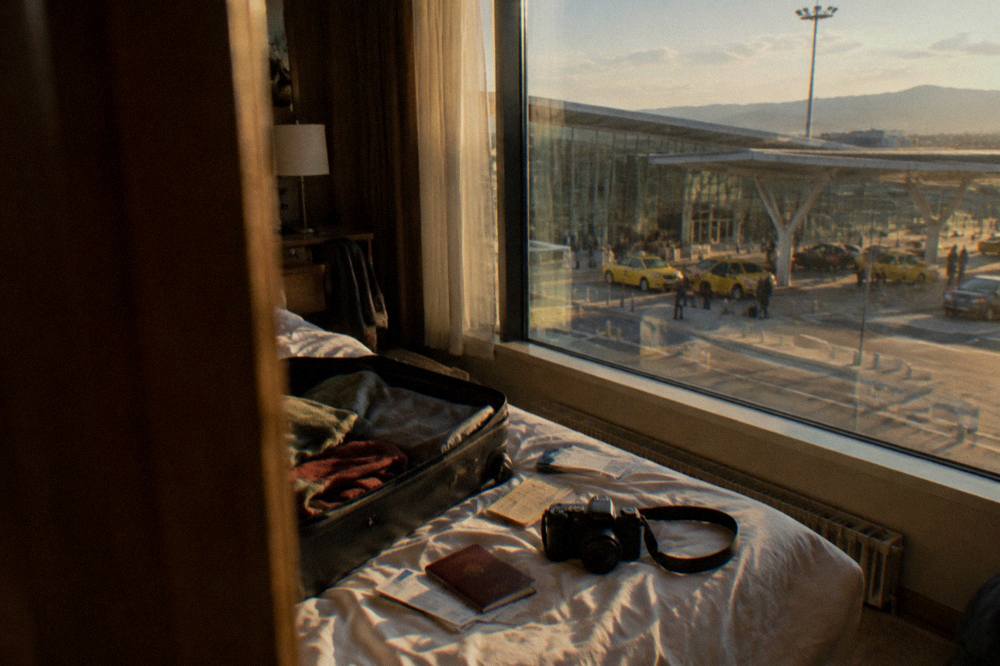 An open suitcase with a passport, tickets and a camera on a hotel bed