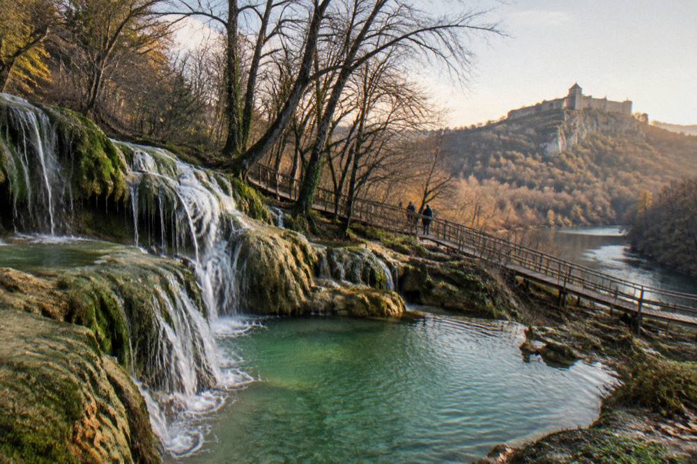A stone fortress hill rising above a river bend at golden hour