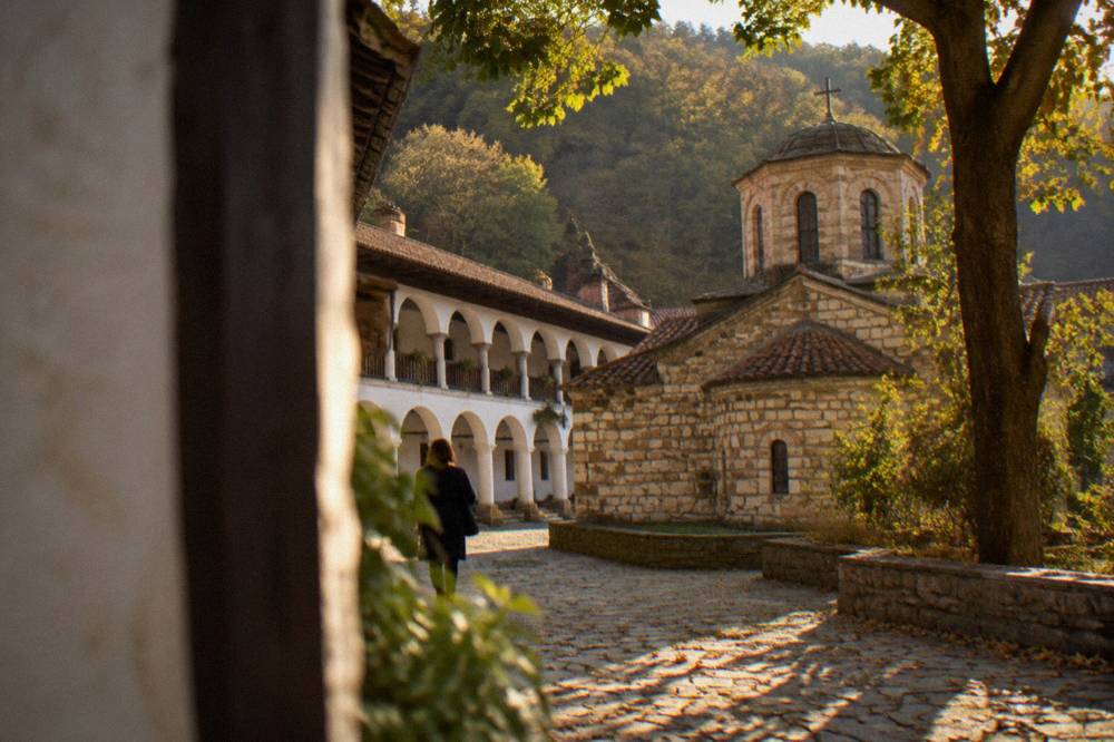 A monastery courtyard with arcades and a small domed church under trees