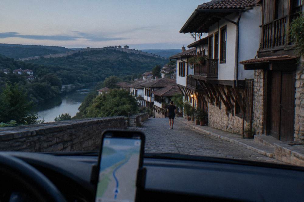 A phone mounted on a car dashboard showing a navigation map on a rural road